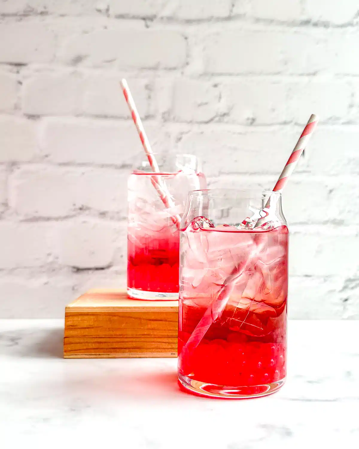 Two summer berry drinks next to each other with straws.