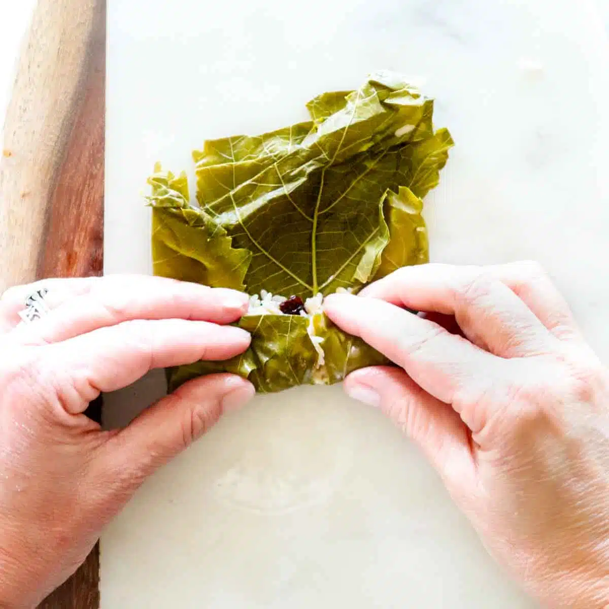 Rolling up a stuffed grape leaf. 