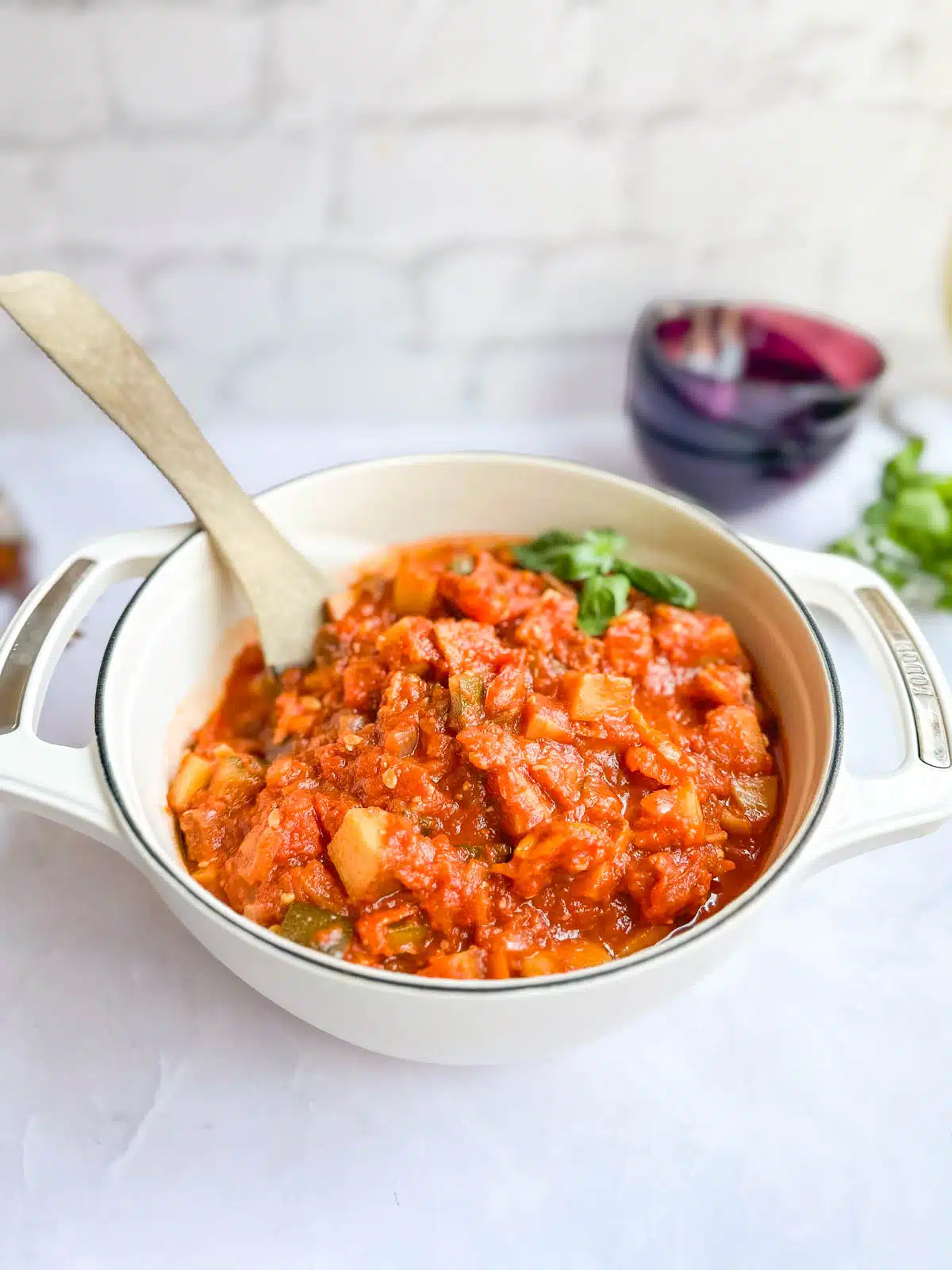 A dutch oven filled with ciambotta garnished with a basil leave