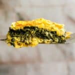 A square of puff pasty spanakopita on a serving spoon.