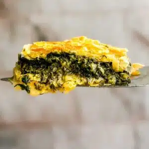 A square of puff pasty spanakopita on a serving spoon.