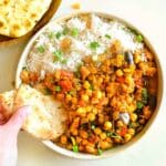 Chickpea tagine served in a bowl with rice and nann bread.