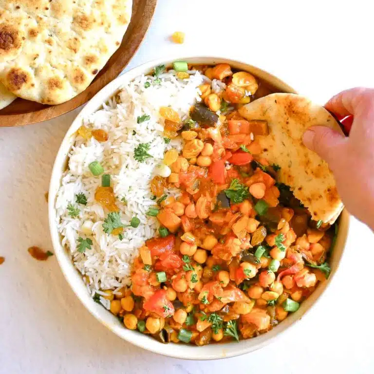 Chickpea tagine served in a bowl with rice and nann bread.