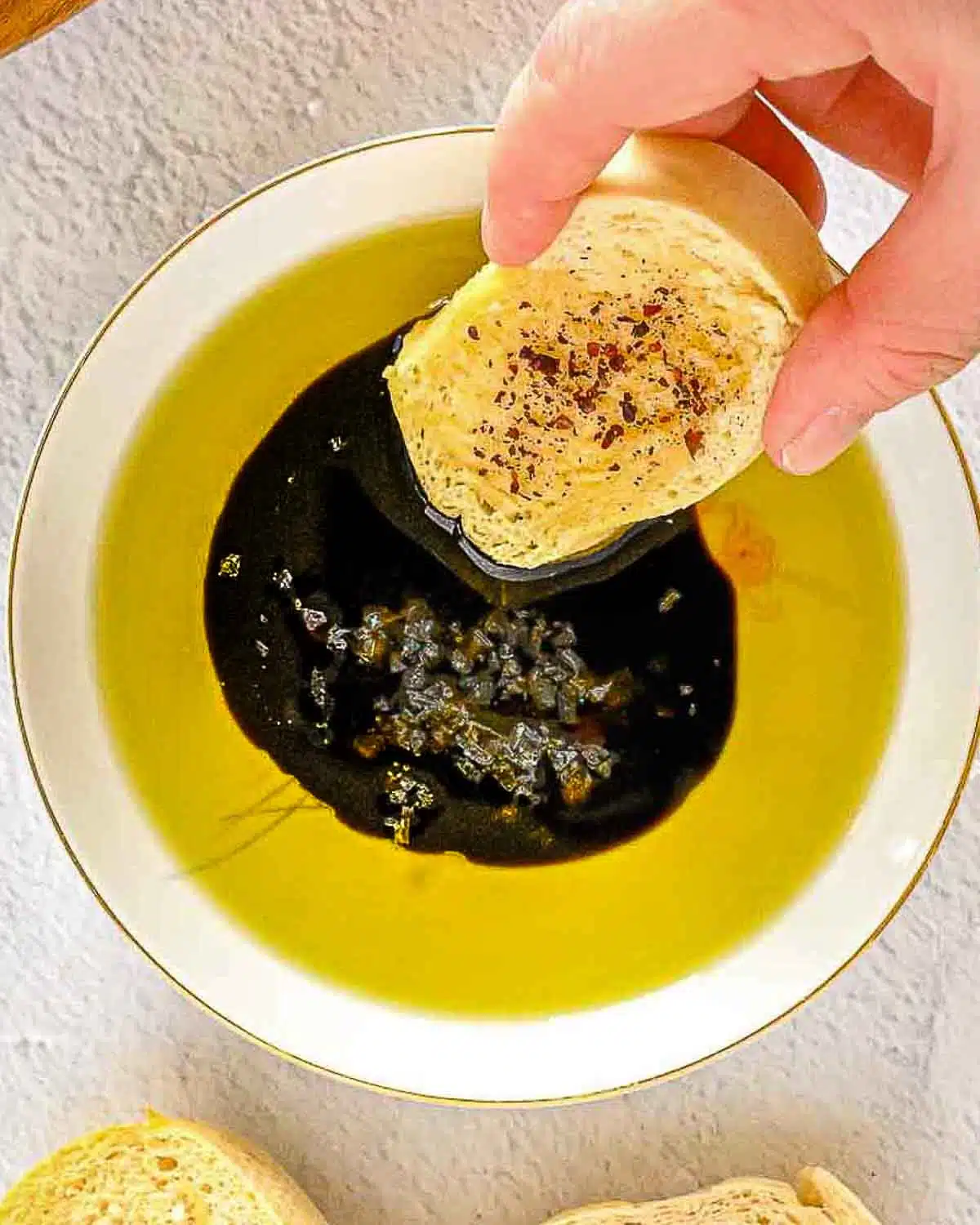 Hand dipping bread into olive oil and vinaigrette.