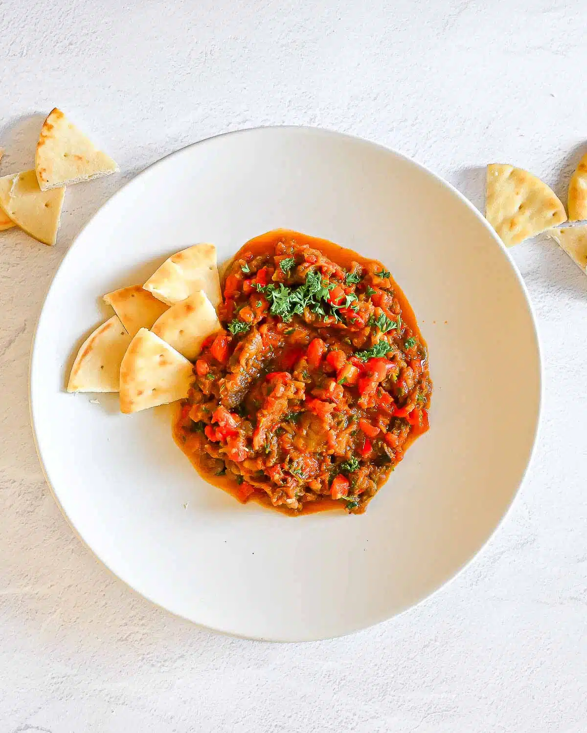 Zaalouk on a plate surrounded with pita triangles.