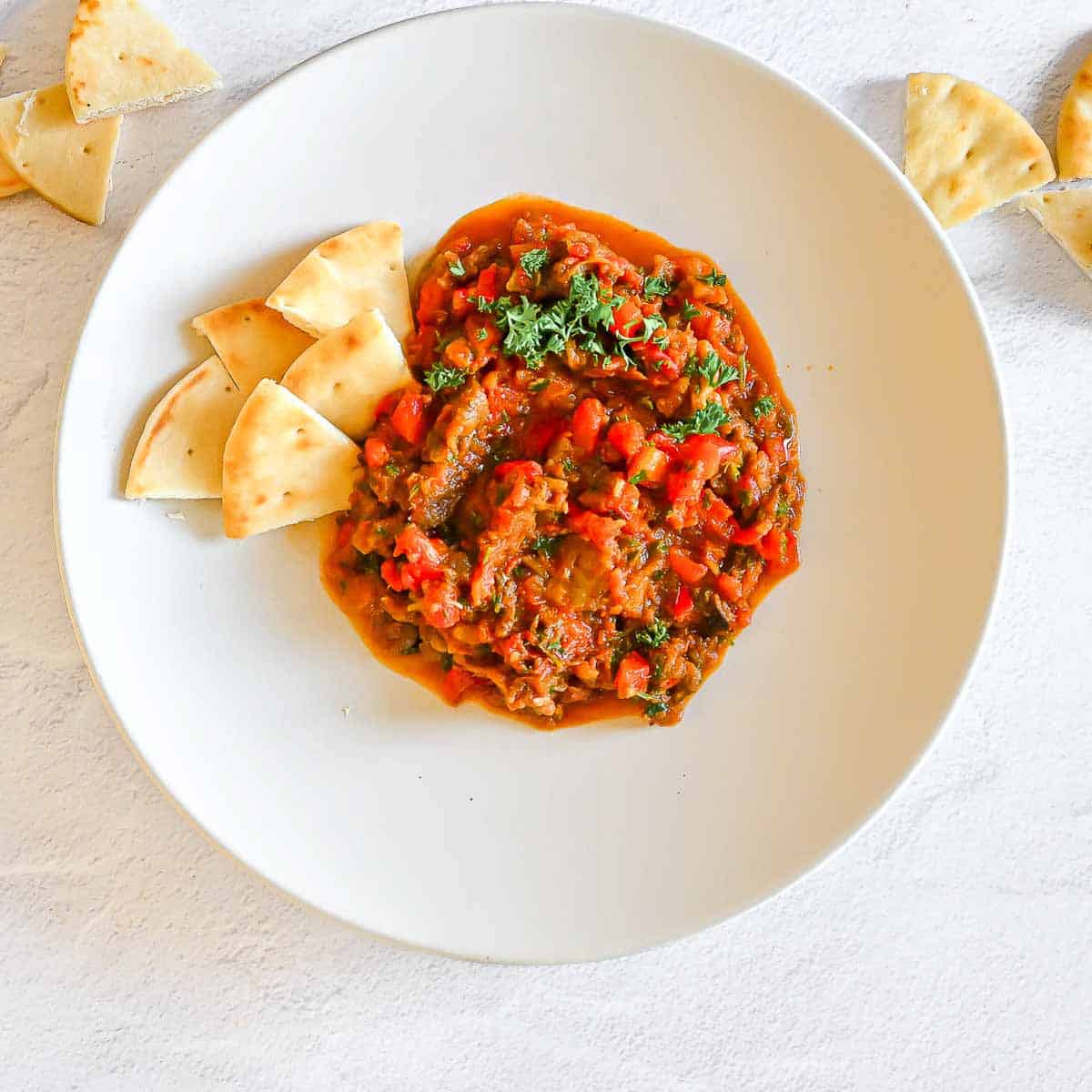 Zaalouk on a plate surrounded with pita triangles.