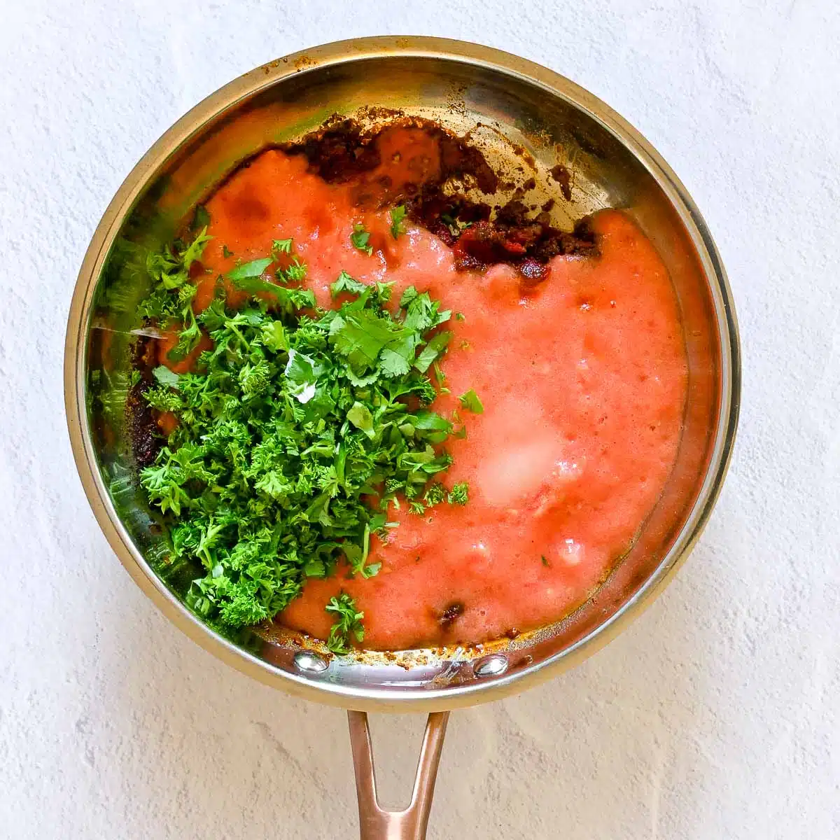 Skilled with spices, tomato juice, parsley and cilantro about to be cooked. 