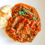 Zaalouk on a plate surrounded by pita triangles.