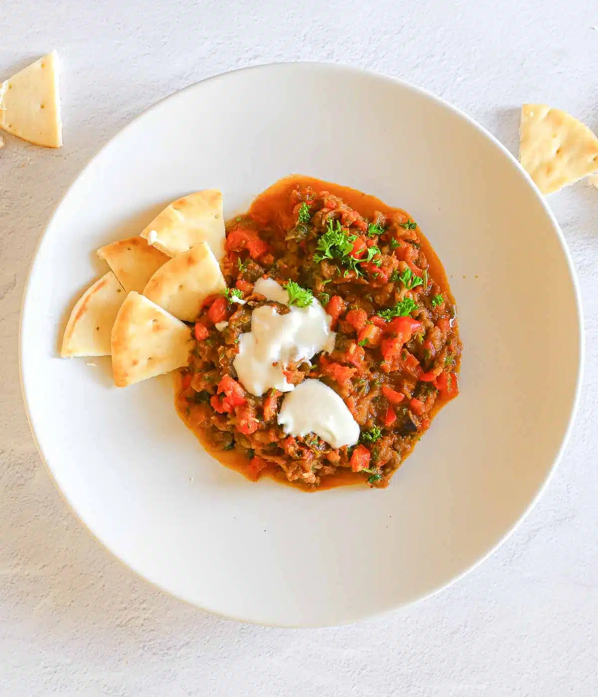 Zaalouk with tahini on top and naan triangles on the plate. 