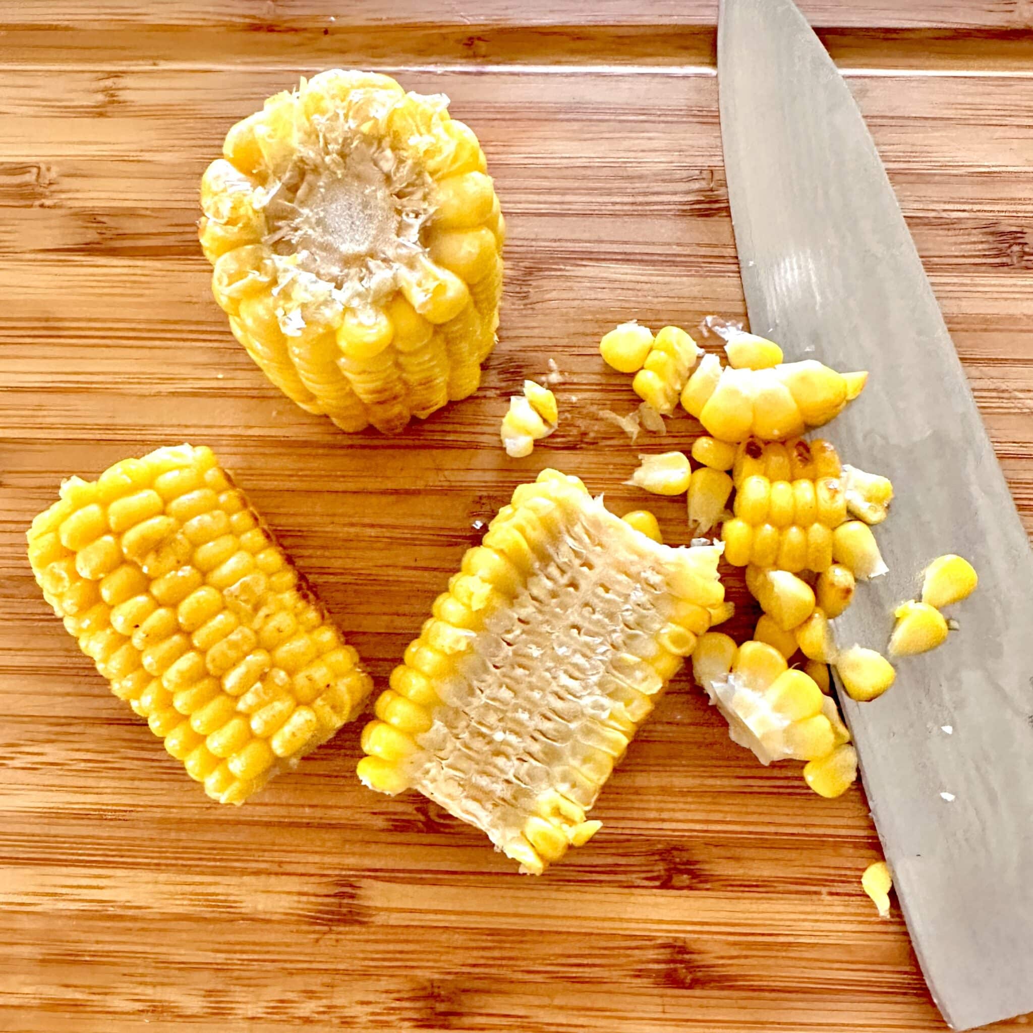 Three roasted corn nibblers on a cutting board with one nibbler sliced
