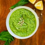 Lemon pesto in a small bowl with pine nuts on top.