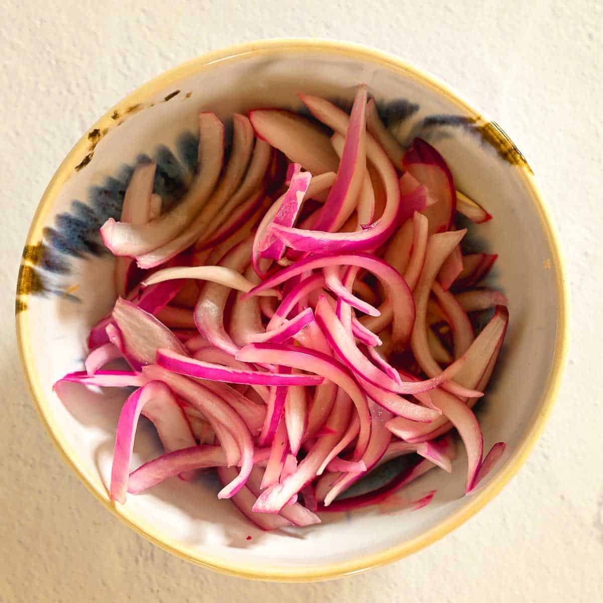 Red onions cut into slivers and marinating in lemon juice.