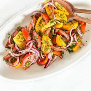 A mix of yellow and red tomatoes, with red onions on a platter.