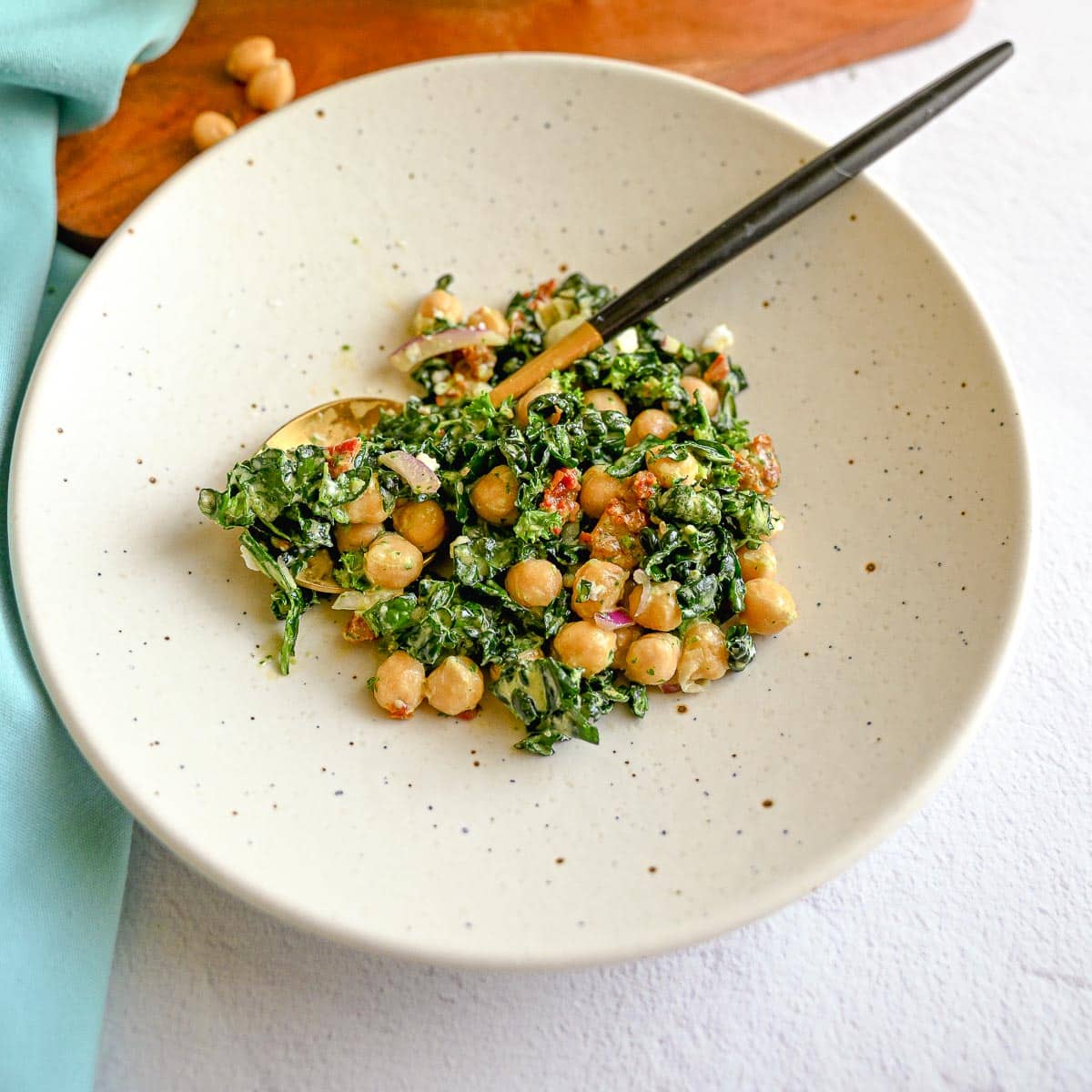 Kale bean salad on a plate with a spoon in it.