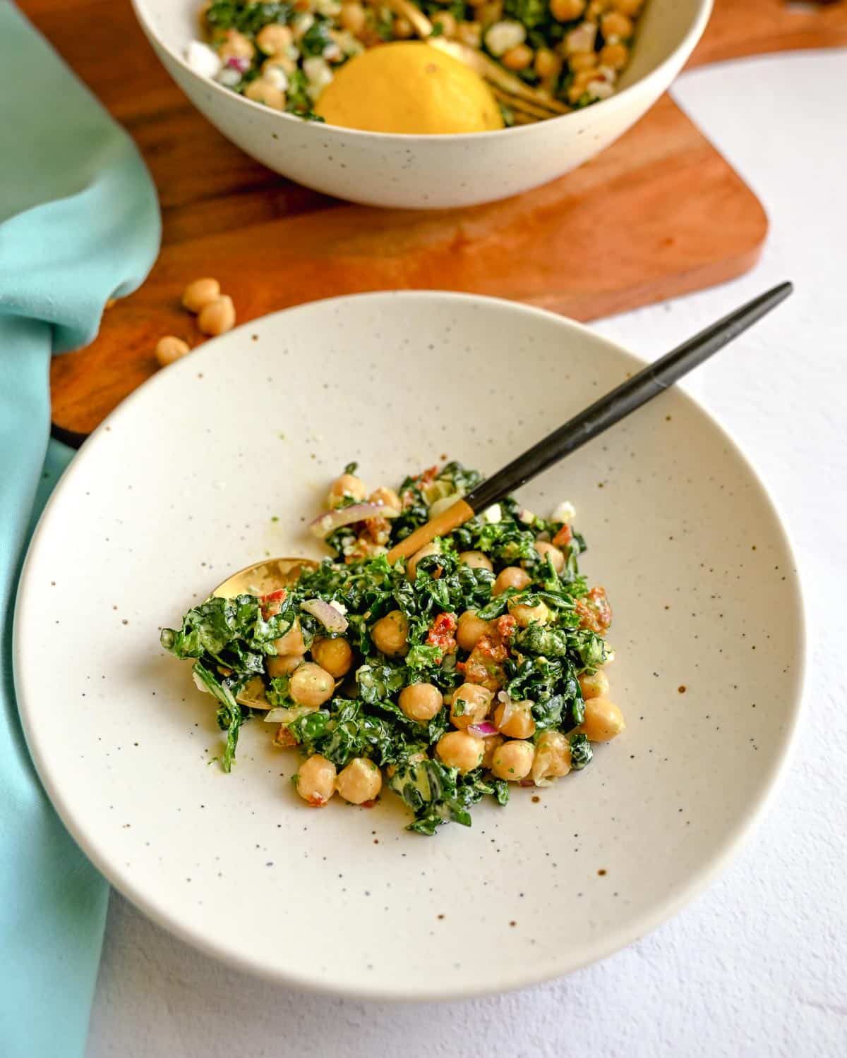 Kale bean salad on a plate with a larger bowl behind it.