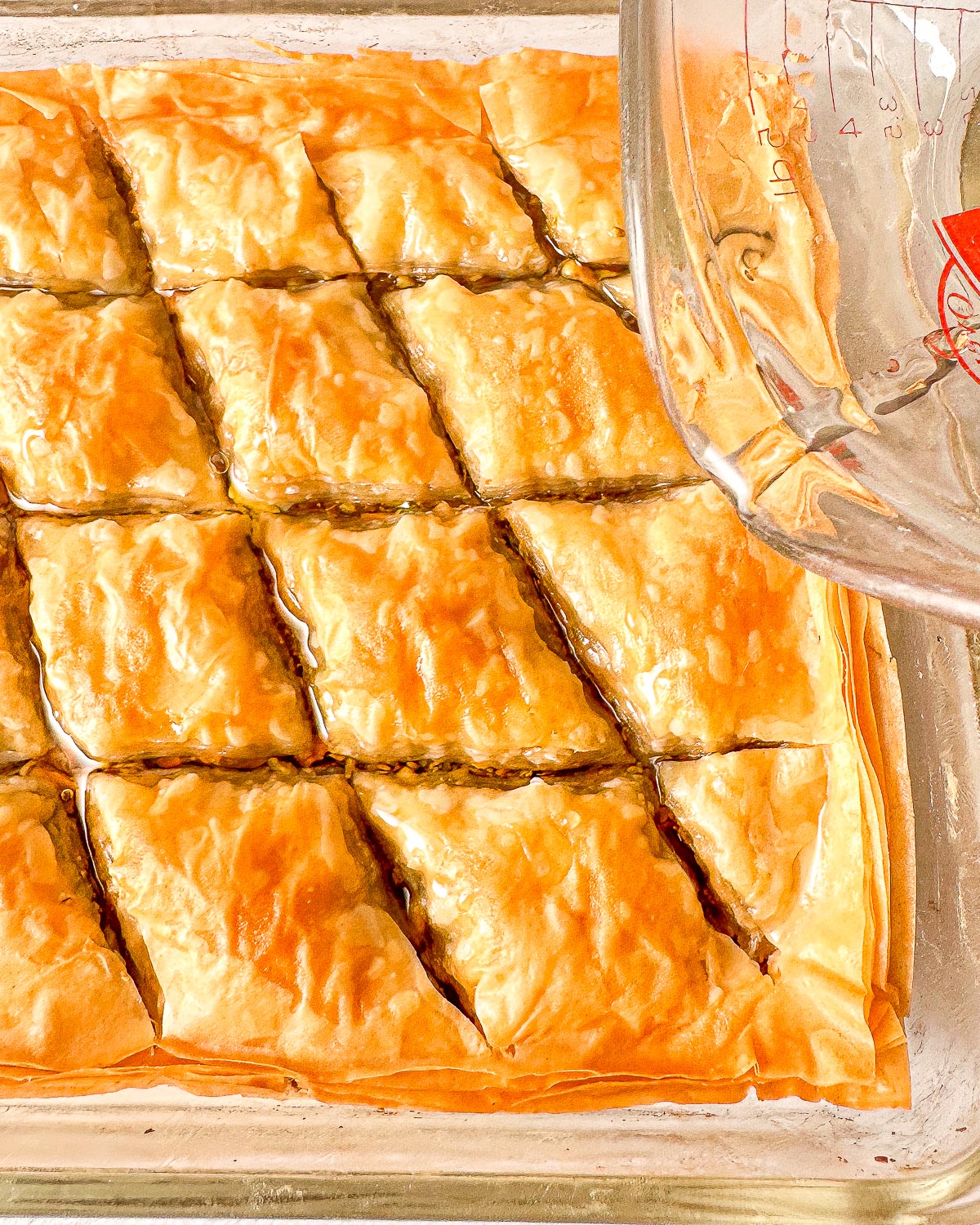 Pouring syrup onto baked pistachio baklava.