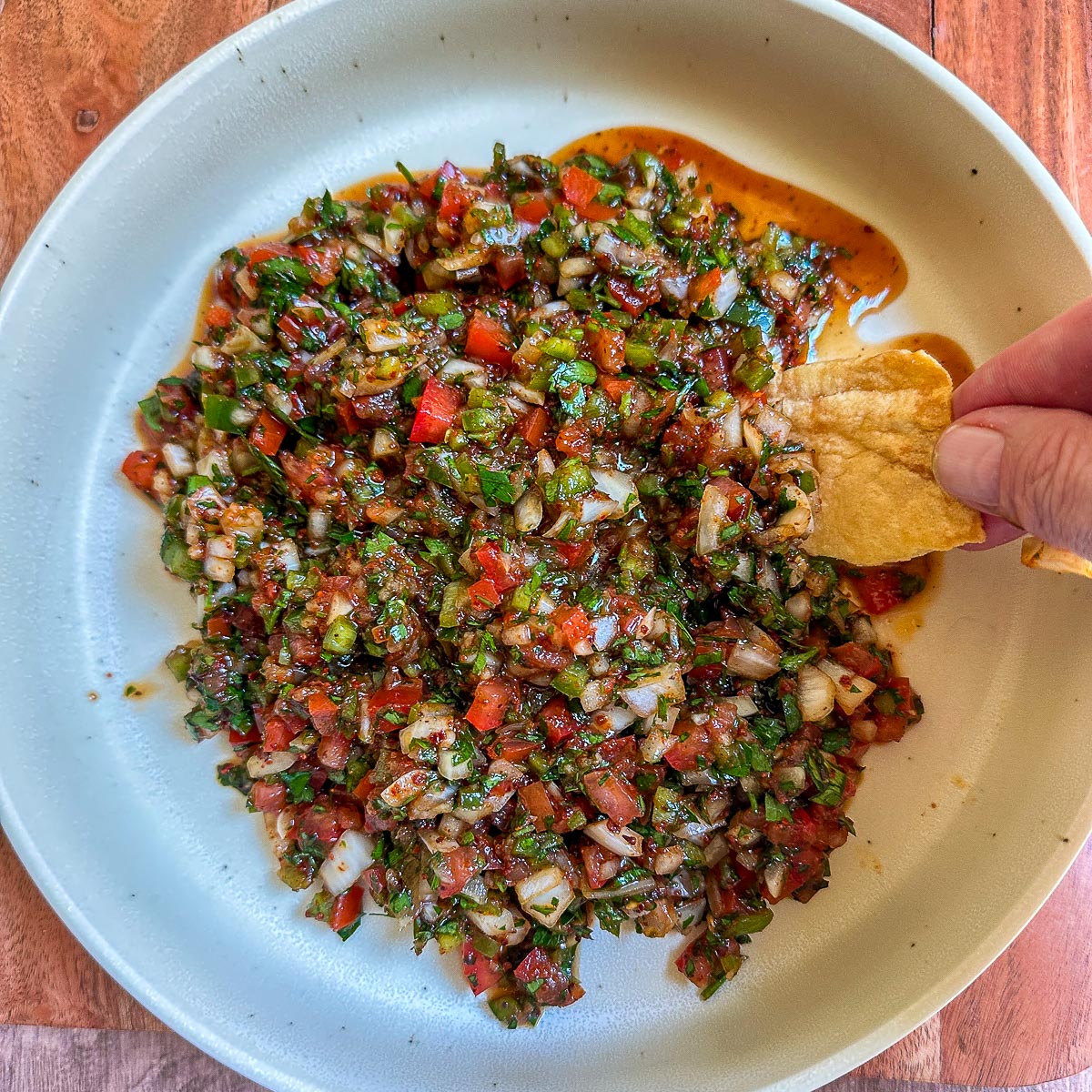 Close-up of Turkish ezme dip with chopped parsley and a pita chip.