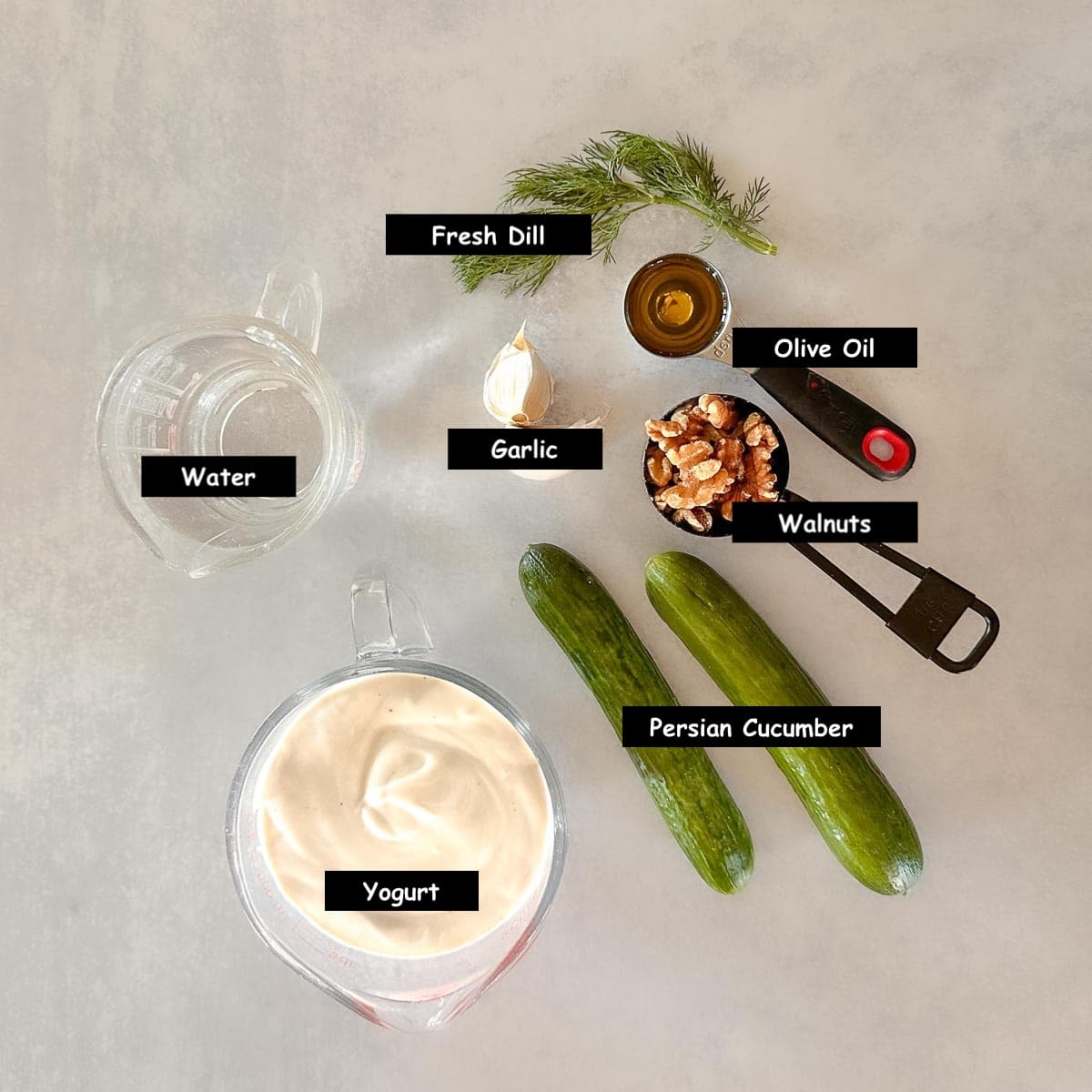Ingredients used to make Bulgarian cold cucumber soup: Persian cucumbers, fresh dill, olive oil, walnuts, yogurt, garlic and water.