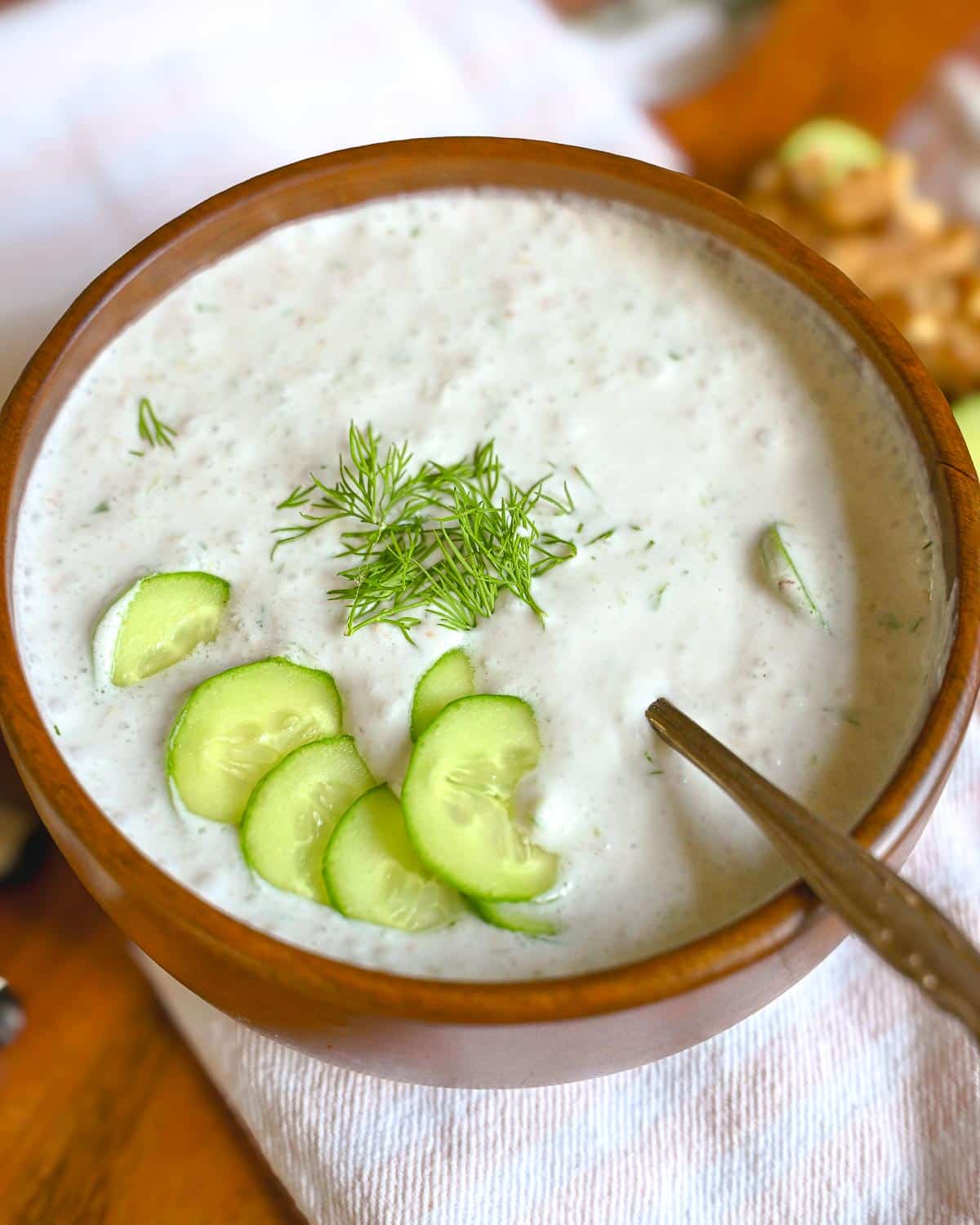 Cold summer cucumber soup with fresh herbs and cucumber slices