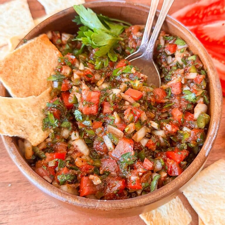Turkish tomato and pepper dip in a bowl with pita chips near it.