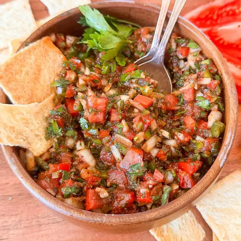 Turkish tomato and pepper dip in a bowl with pita chips near it.