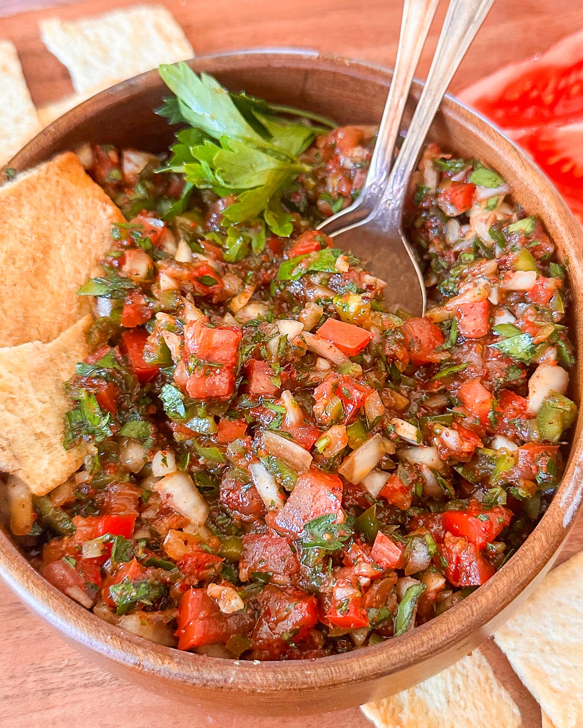 Up close picture of Turkish ezme in a bowl with pita chips near it.