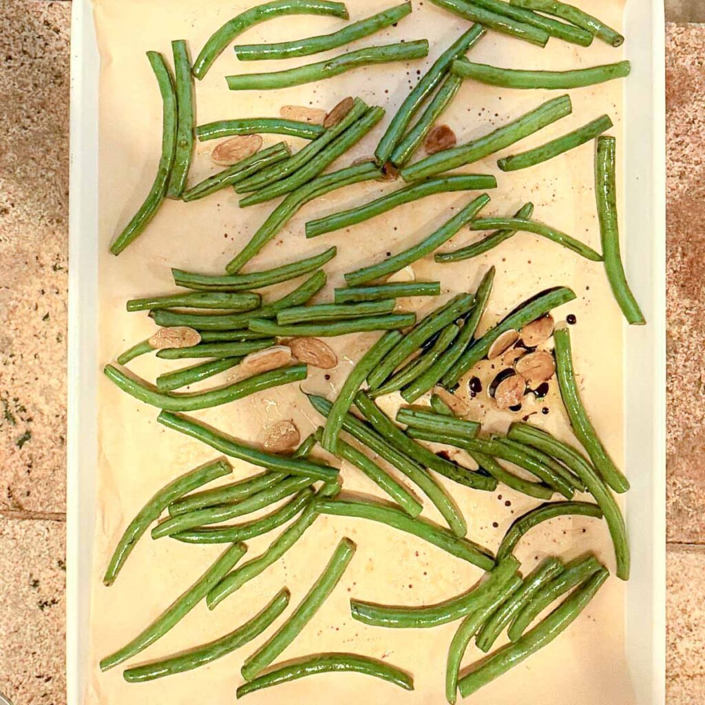 A baking tray filled with green beans about to go into the oven.