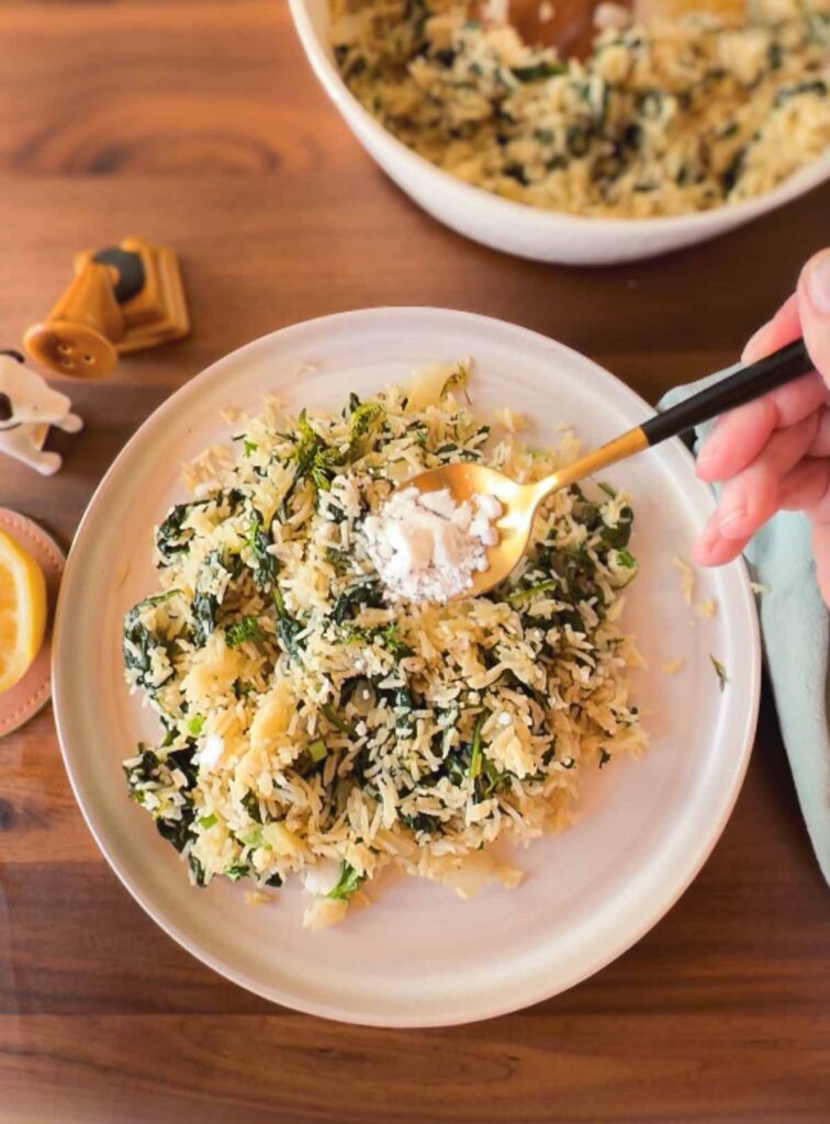 Adding vegan feta cheese to rice with spinach, lemon and dill.