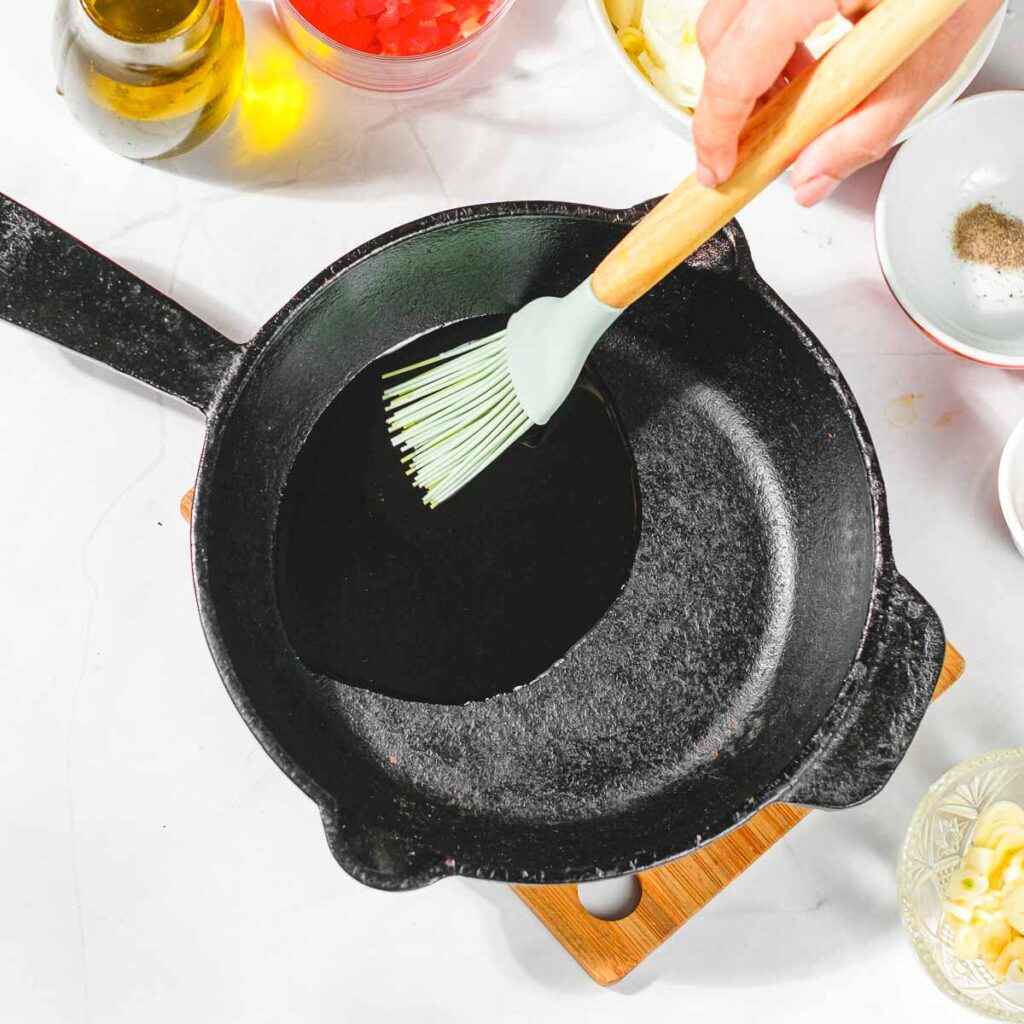 Adding olive oil to a cast-iron pan.