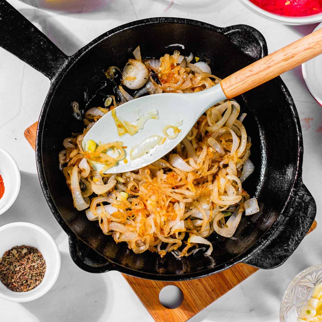 A spoon in a cast iron skillet with sautéed onions