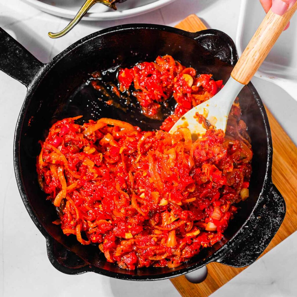 A spoon in a cast iron with prepared Imam Bayildi filling.
