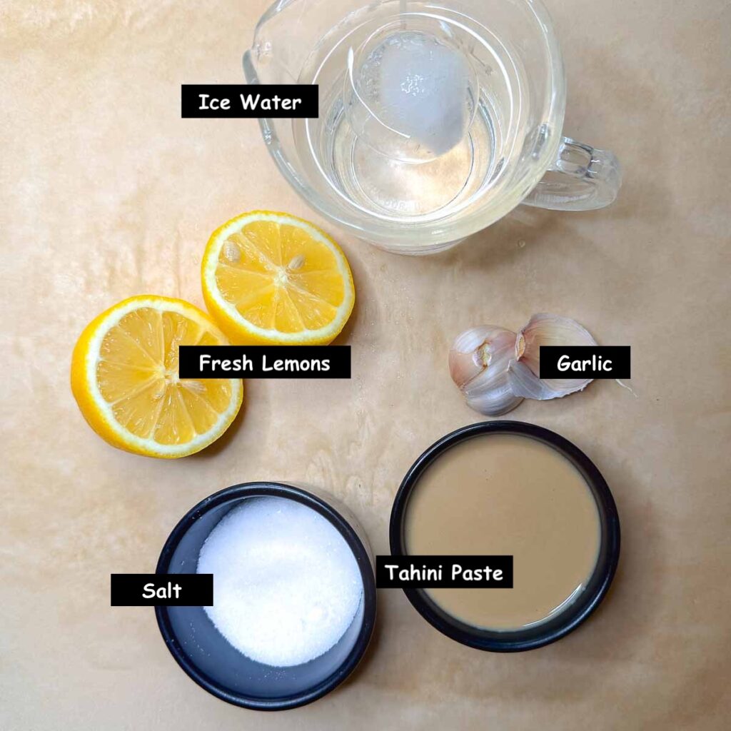 Ingredients used in making tahini sauce (tahini paste, lemon juice, garlic, salt and ice water).