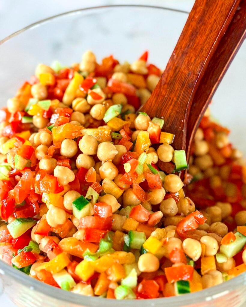 A balela salad in a a salad bowl with salad tongs.