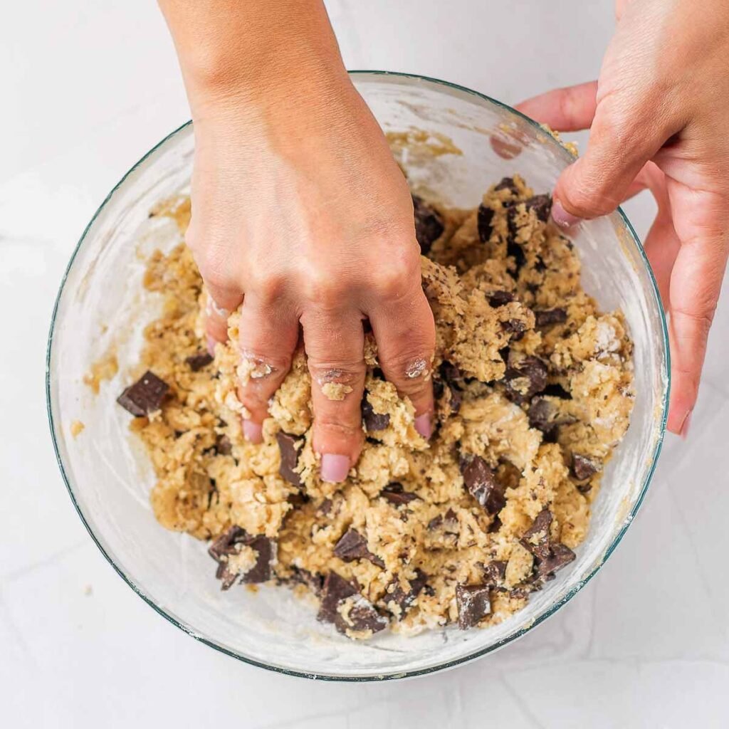 A hand mixing vegan cookie dough together.