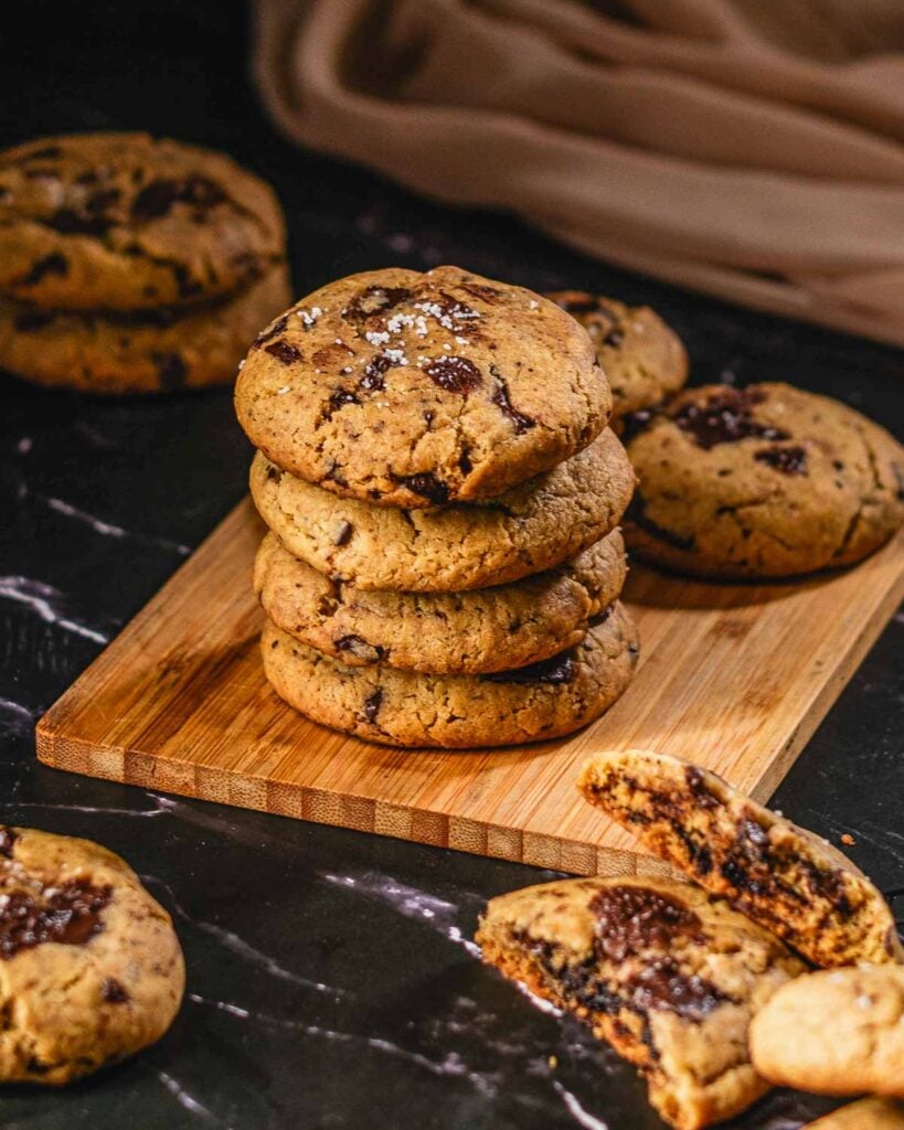 A stack of baked vegan tahini cookies with flaky sea salt on top.