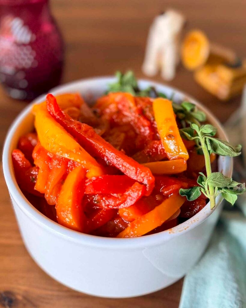 A white bowl filled with peperonata, stewed Italian bell peppers.