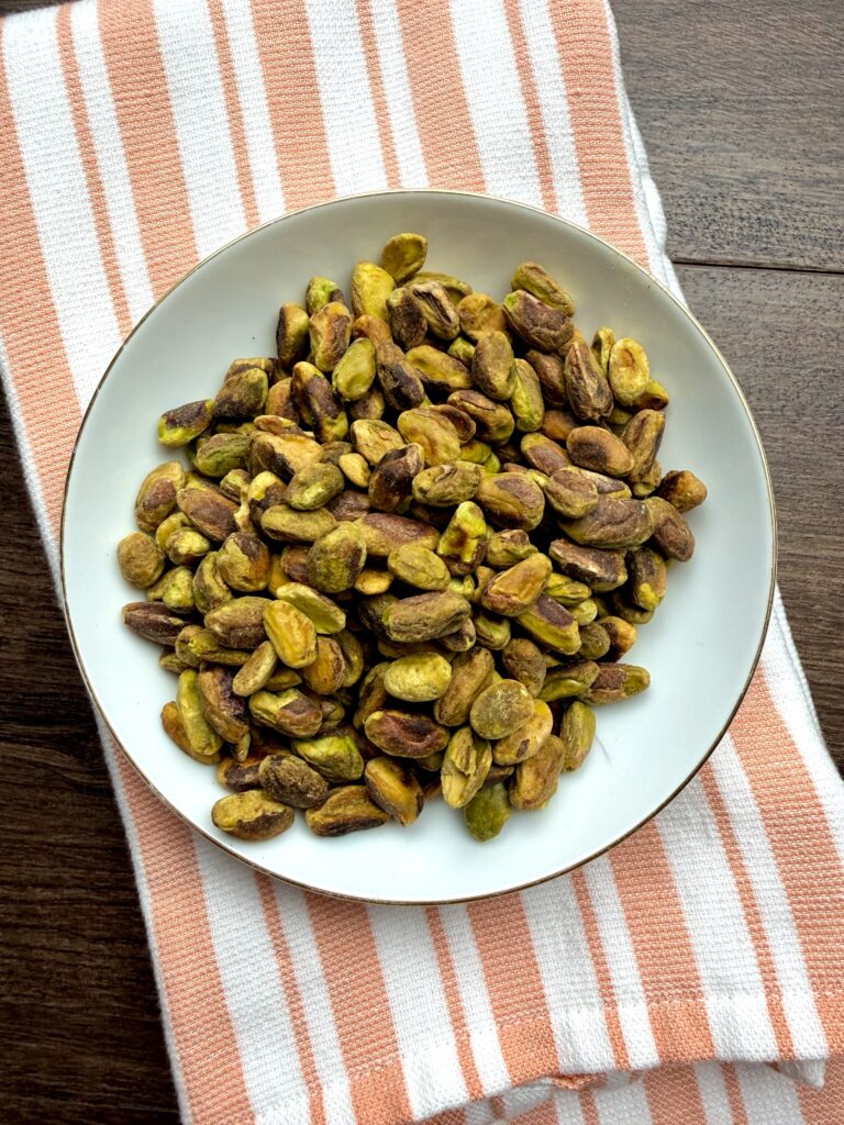 Toasted pistachios in a white bowl.