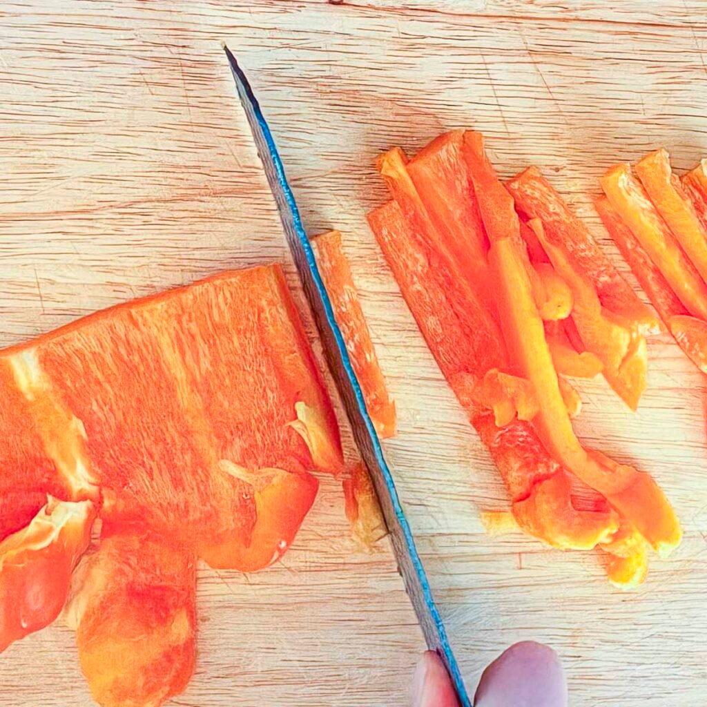 Slicing an orange bell pepper.