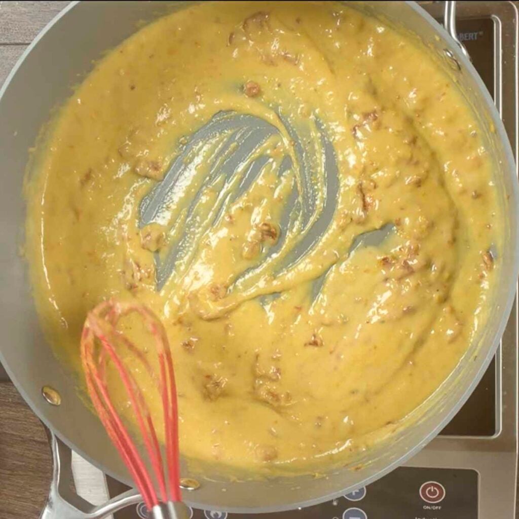 Creamy vegan pasta with nutmeg, nutritional yeast, salt, and pepper has been whisked in.
