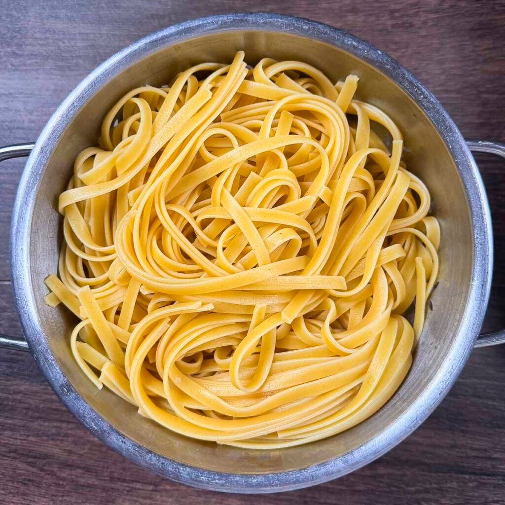 Fettuccine noodles drained in a colander.