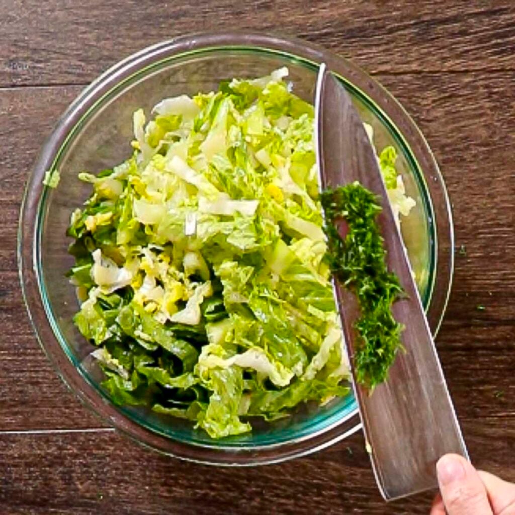 Adding finely chopped fresh dill to maroulosalata.