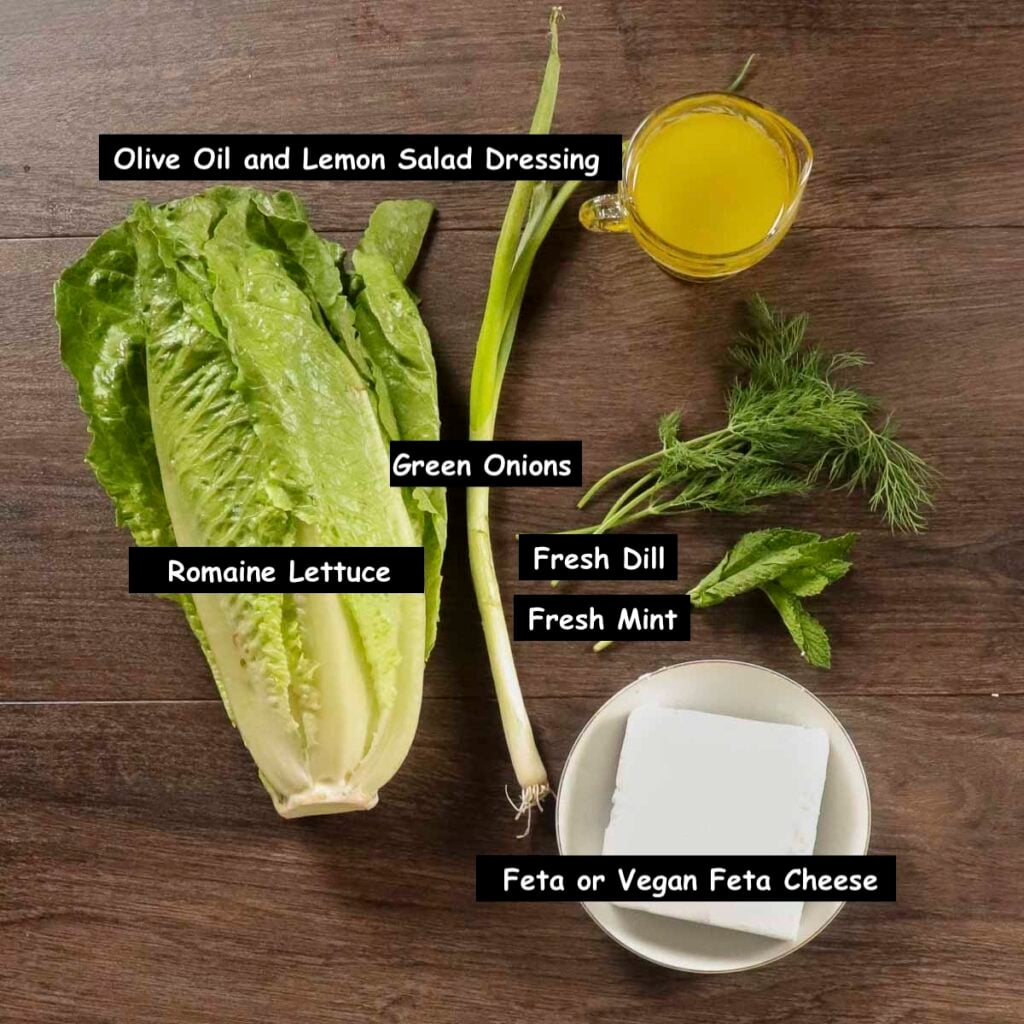 Ingredients used in making a Greek maroulosalata salad (romaine lettuce, green onions, fresh dill, fresh mint, feta or vegan feta cheese and a olive oil and lemon salad dressing).