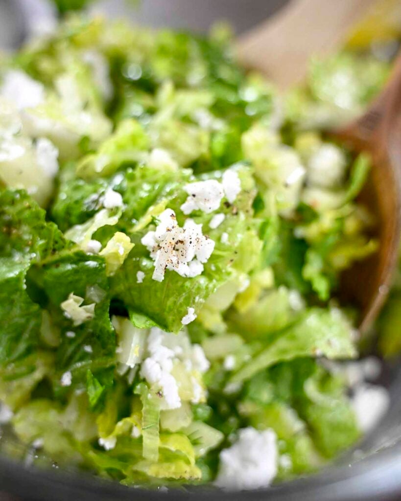 Maroulosalata salad in a large bowl topped with feta cheese.