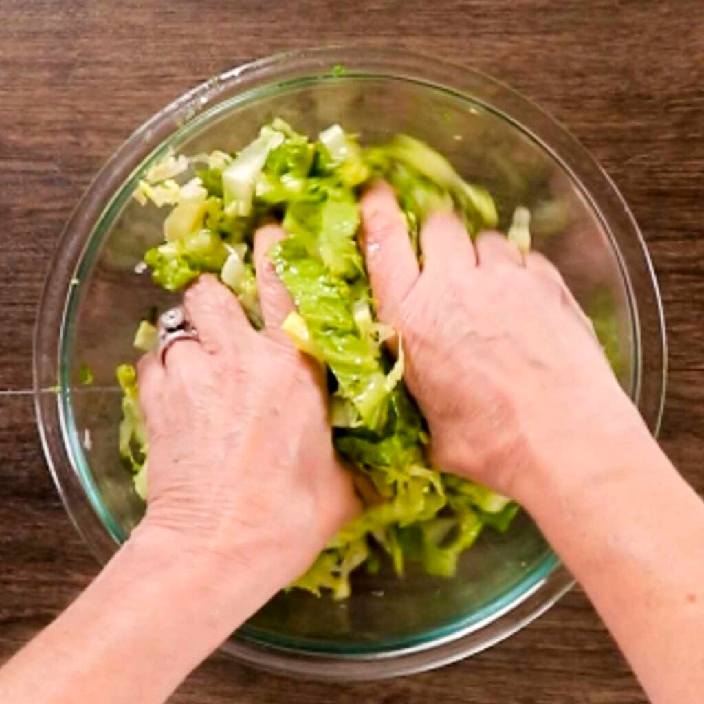 Massing the romain lettuce as part of making Adding finely chopped fresh dill to maroulosalata Greek salad.