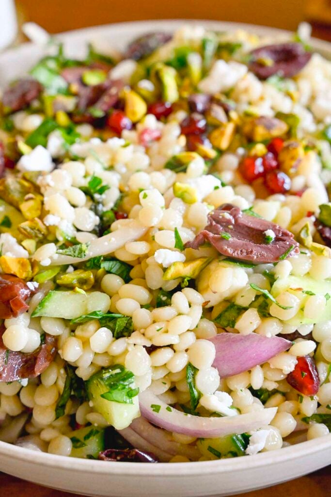 A plate with a couscous salad filed with Mediterranean ingredients up close