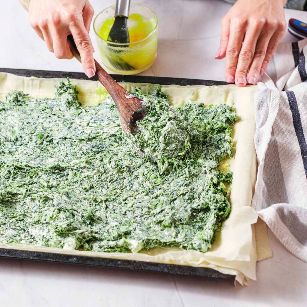 Add in the spinach filling to phyllo dough to make vegan spanakopita.