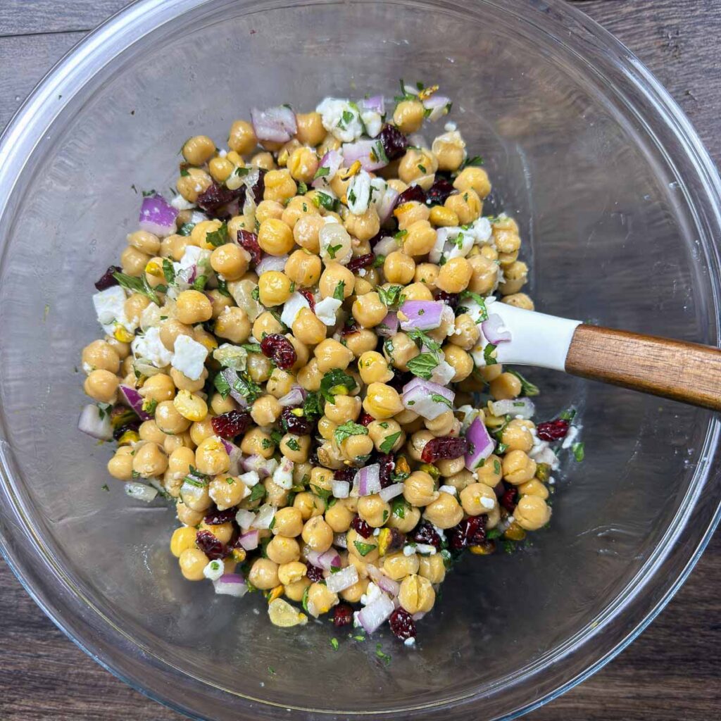 Tossing all the ingredients for a cranberry and chickpea salad together in a glass bowl.