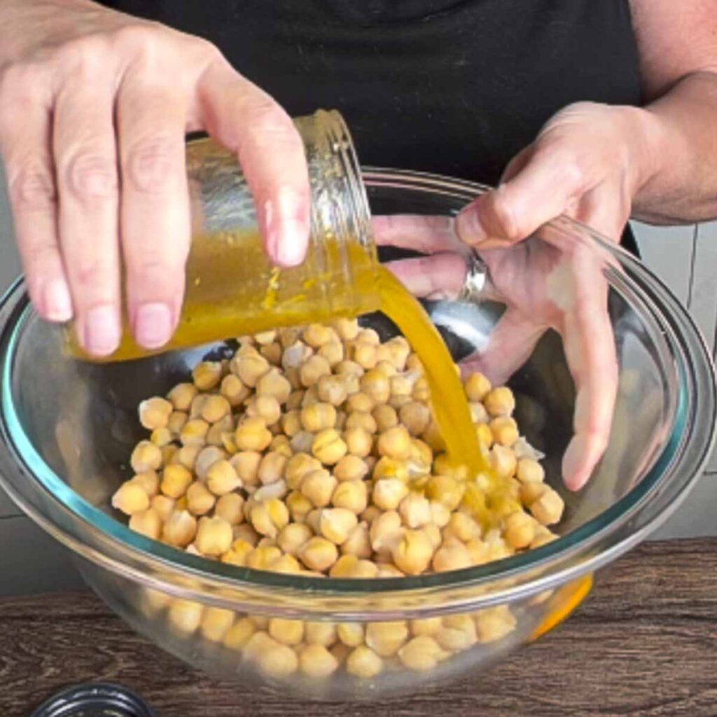 Adding orange za'atar dressing to warm toasted chickpeas.