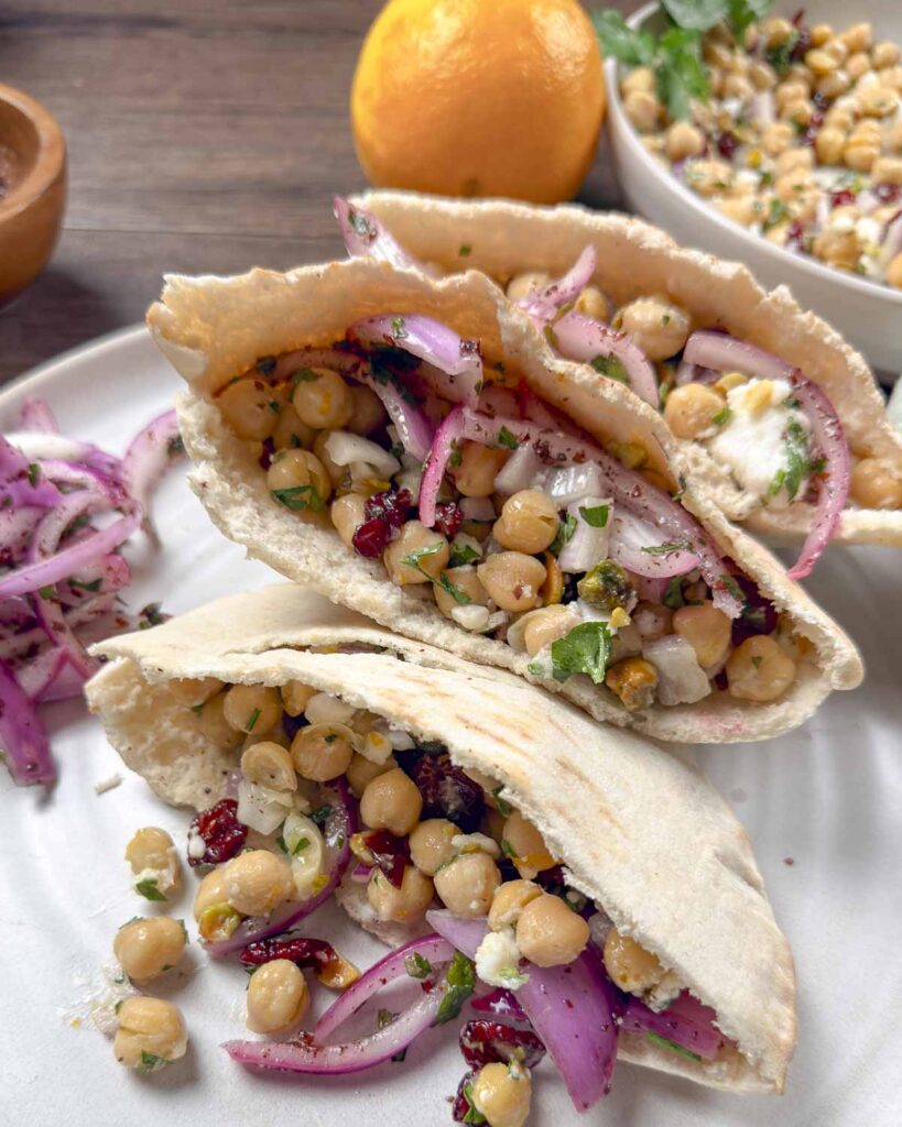 Three pita pockets filled with sumac onions, chickpeas, cranberry, and feta salad.