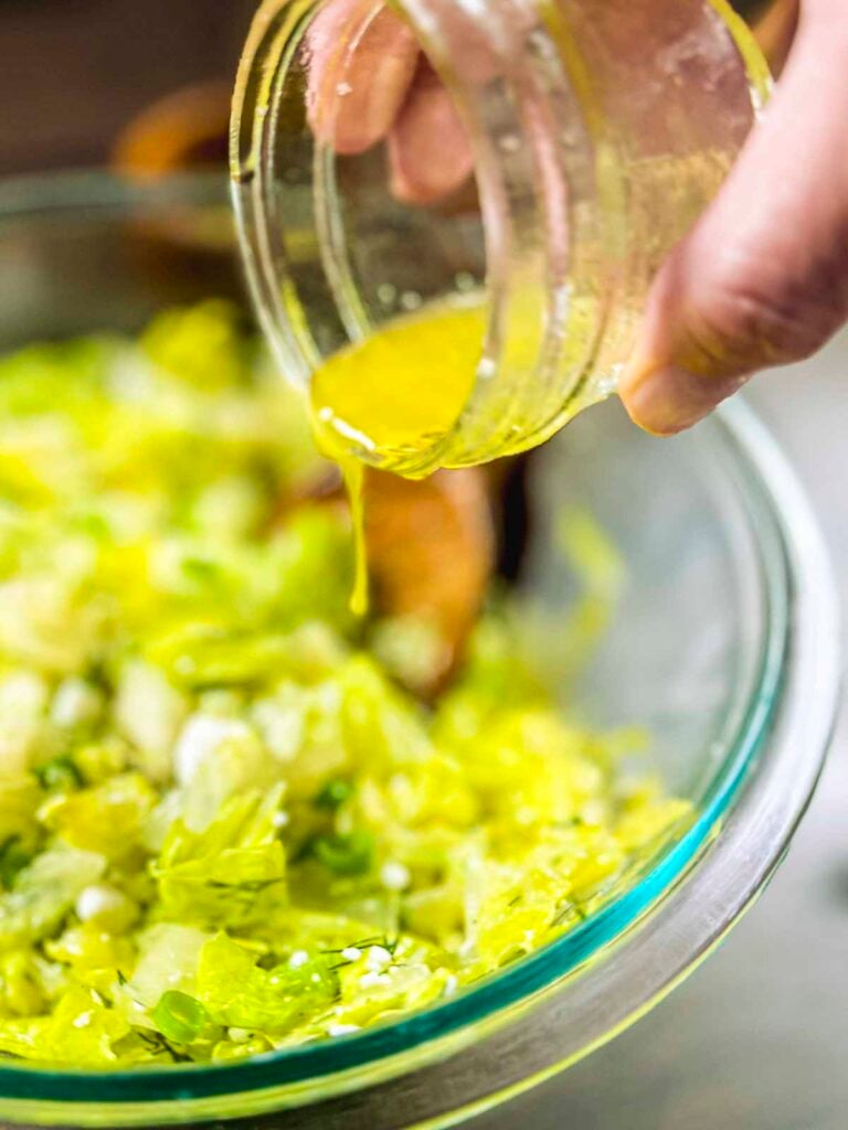 Ladolemono being poured on a maroulosalata (Greek lettuce salad)
